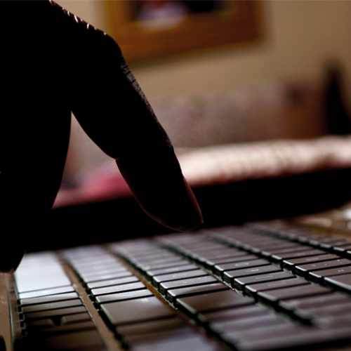 A dark photo of a person's hands typing on a laptop