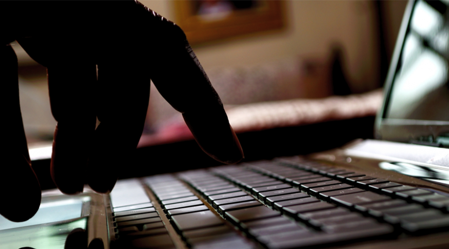 A dark photo of a person's hands typing on a laptop