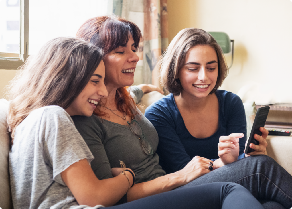 Mom and two daughters looking at a Bark Phone for kids