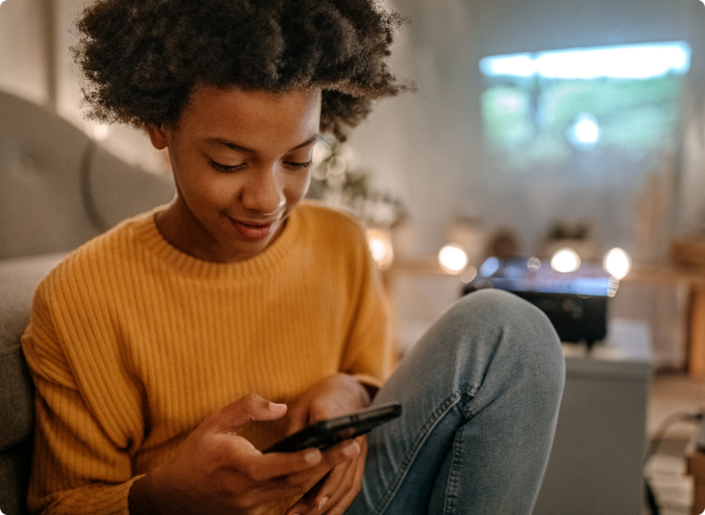 Girl in yellow sweater holding the Bark Kids' Phone