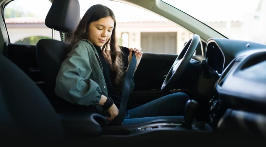 image of teen girl buckling up in car driver's seat