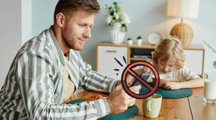 father on his phone at the breakfast table
