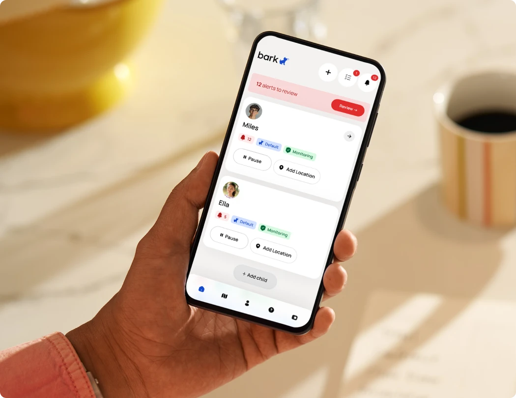 A parent holding a phone showing the Bark App