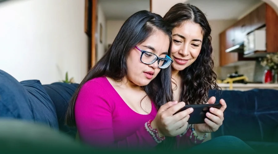 Two young women sitting on a couch looking at a phone together