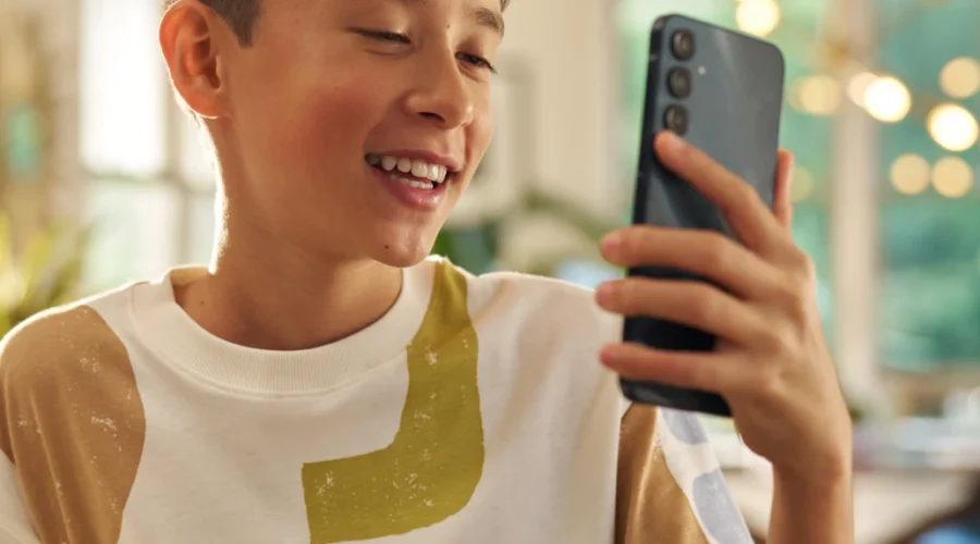 Smiling boy holding up a phone at home