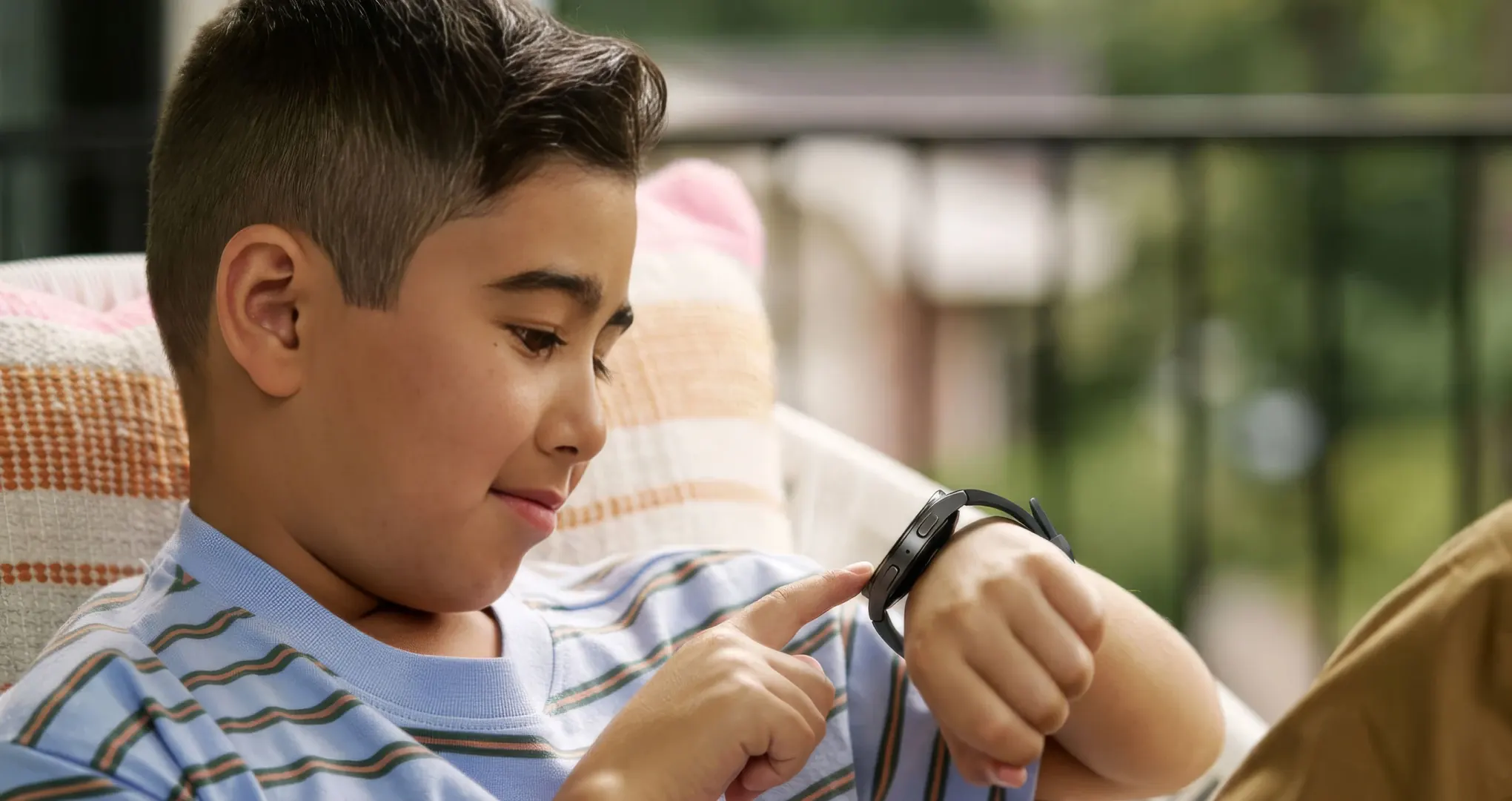 A boy on a porch chair tapping his Bark Watch